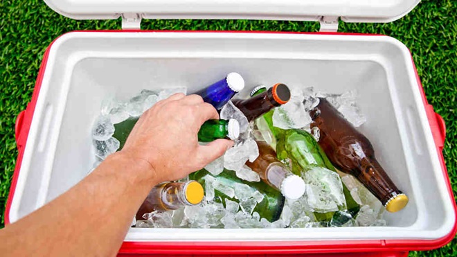Hand taking bottle from ice filled cooler